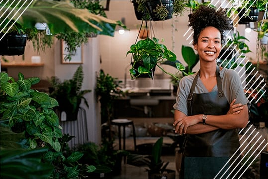 Mujer alegre en su negocio mostrando su emprendimiento de plantas.